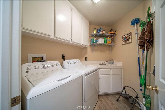 laundry room with sink, light hardwood / wood-style floors, separate washer and dryer, and cabinets