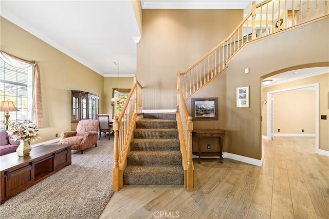 stairway featuring a wealth of natural light, crown molding, and wood-type flooring