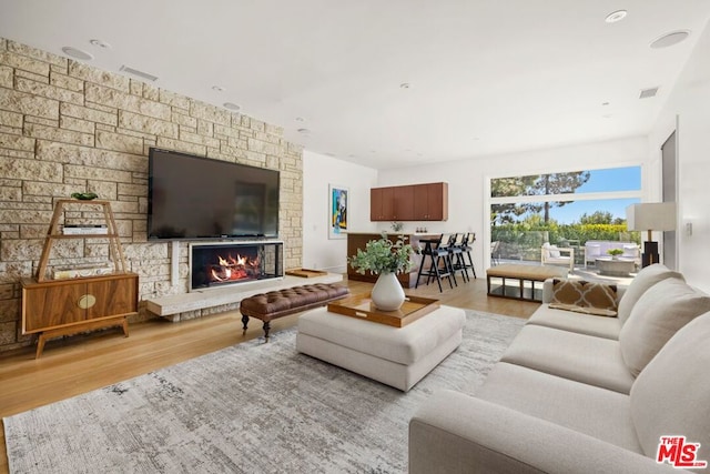 living room with a stone fireplace and light hardwood / wood-style flooring