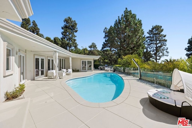 view of swimming pool with a patio and french doors