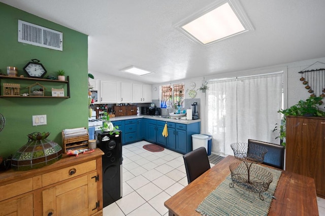 kitchen with a textured ceiling, light tile patterned floors, white cabinetry, and blue cabinetry