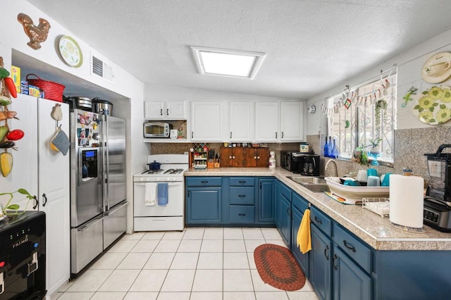 kitchen featuring appliances with stainless steel finishes, white cabinetry, blue cabinetry, lofted ceiling, and sink