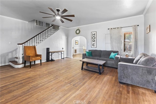 living room featuring crown molding, baseboards, stairs, wood finished floors, and arched walkways