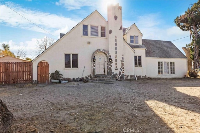 back of house featuring stucco siding and fence