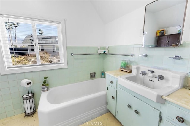 bathroom with tile patterned flooring, vanity, a bath, and tile walls