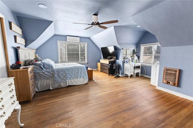 bedroom featuring lofted ceiling, heating unit, a wall mounted air conditioner, wood-type flooring, and ceiling fan