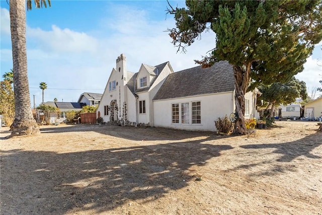 back of property featuring a chimney and stucco siding