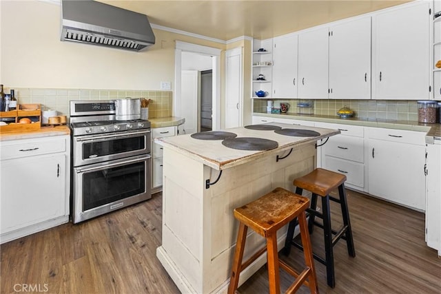 kitchen featuring white cabinetry, open shelves, wall chimney range hood, and range with two ovens