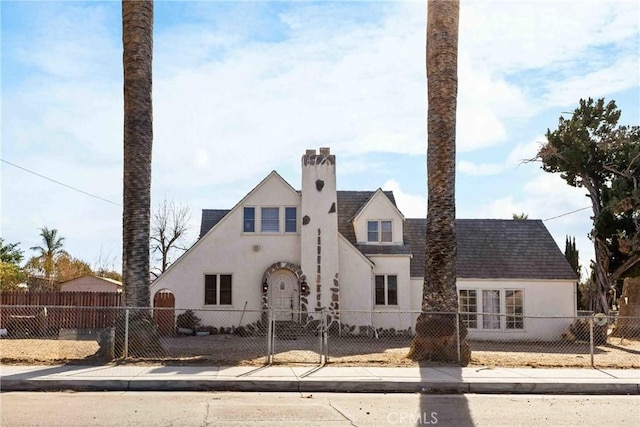 view of front of home featuring a fenced front yard, stucco siding, and a chimney