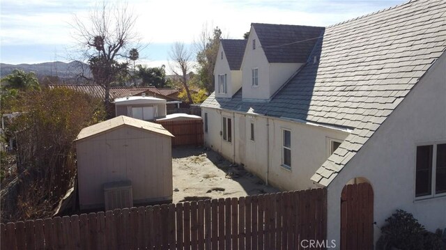 view of side of home with a shed and a mountain view