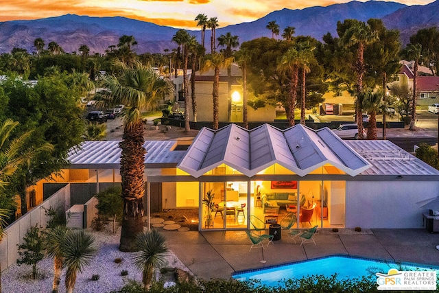 back house at dusk with a mountain view and a patio