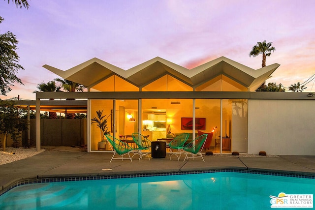 pool at dusk with a patio area