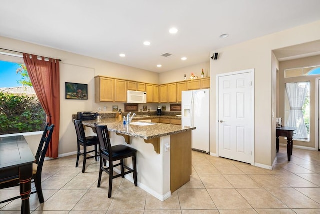 kitchen with kitchen peninsula, sink, white appliances, light tile patterned flooring, and light stone counters