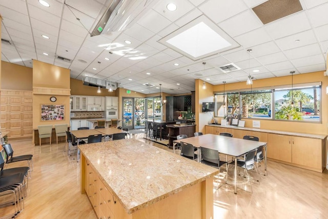 kitchen with a drop ceiling, light stone countertops, plenty of natural light, and a spacious island