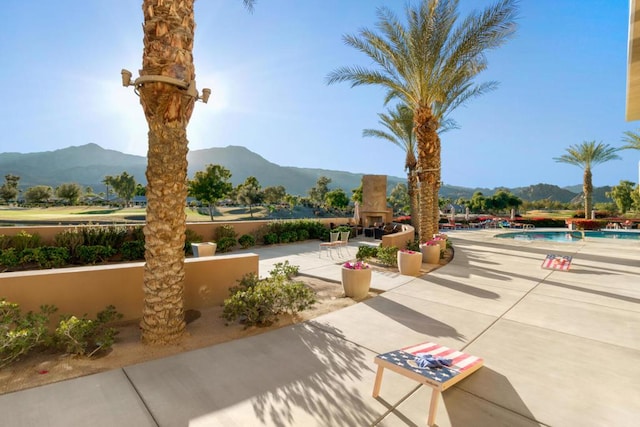 surrounding community with a swimming pool, a mountain view, and a patio