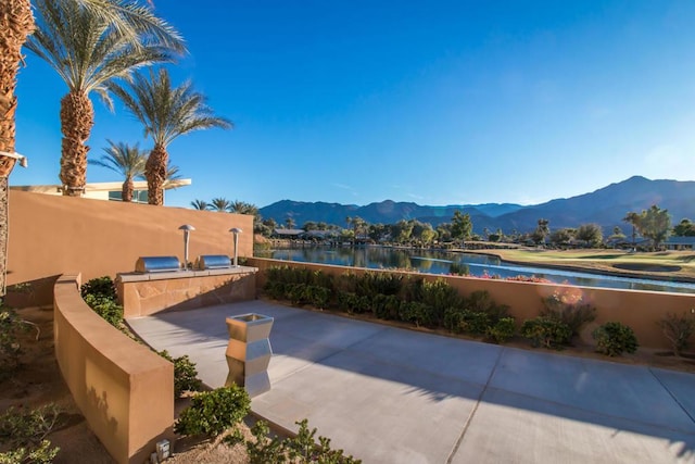 view of patio with a water and mountain view and an outdoor kitchen