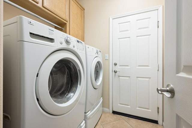 laundry room with washing machine and dryer, cabinets, and light tile patterned flooring