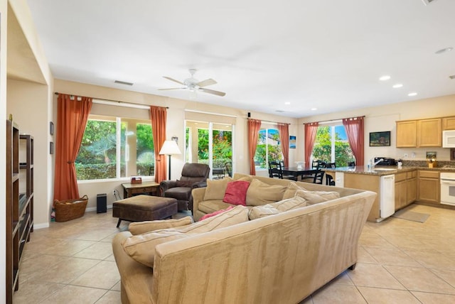 living room with a wealth of natural light, light tile patterned flooring, and ceiling fan