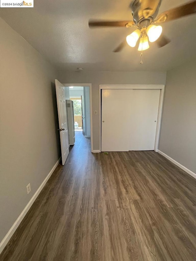 unfurnished bedroom featuring a textured ceiling, dark hardwood / wood-style floors, ceiling fan, and a closet