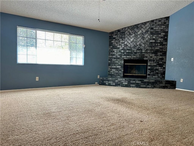 unfurnished living room featuring lofted ceiling, a fireplace, carpet floors, and a textured ceiling