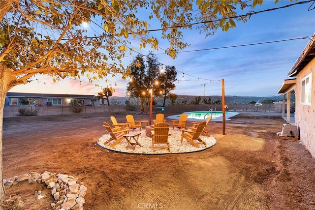 yard at dusk with a fenced in pool and a fire pit