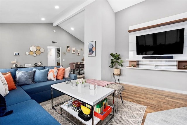 living room featuring high vaulted ceiling, light hardwood / wood-style floors, and beam ceiling