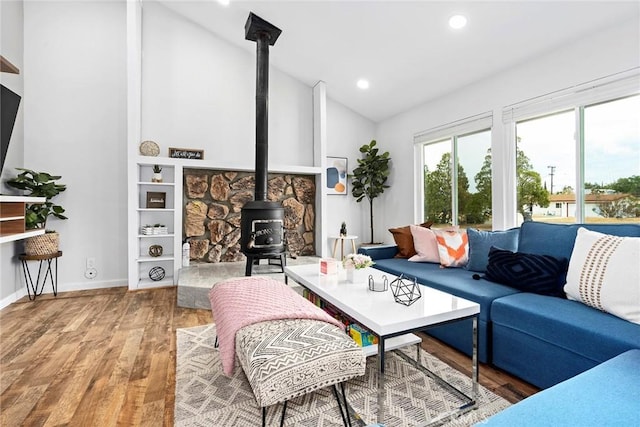 living room with lofted ceiling, wood-type flooring, and a wood stove