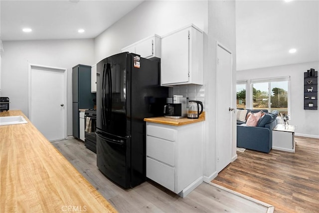 kitchen with tasteful backsplash, black appliances, white cabinets, light hardwood / wood-style flooring, and sink