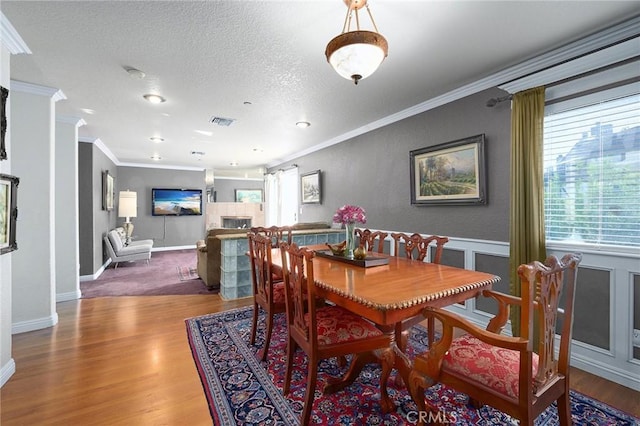 dining space featuring a textured ceiling, wood-type flooring, and crown molding