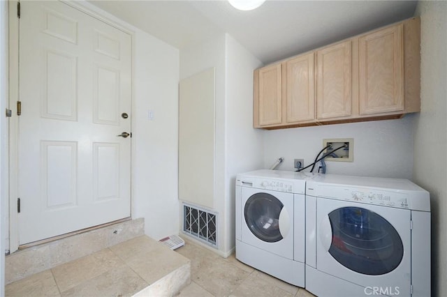 clothes washing area with washer and clothes dryer, light tile patterned flooring, and cabinets