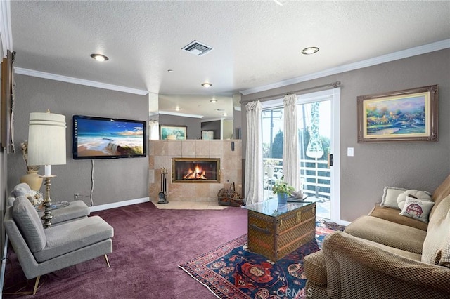 living room with a tiled fireplace, crown molding, carpet floors, and a textured ceiling