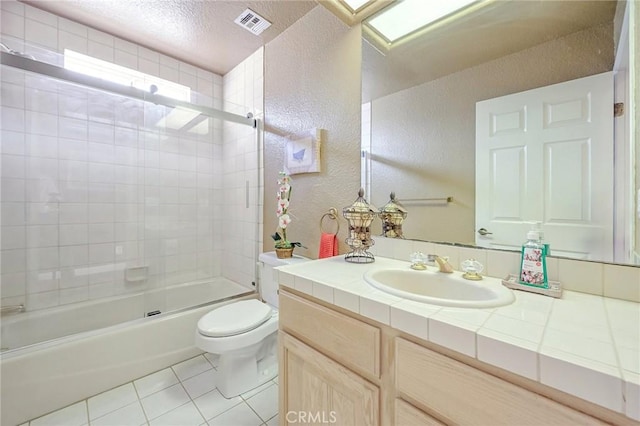 full bathroom with tile patterned floors, vanity, tiled shower / bath, and toilet