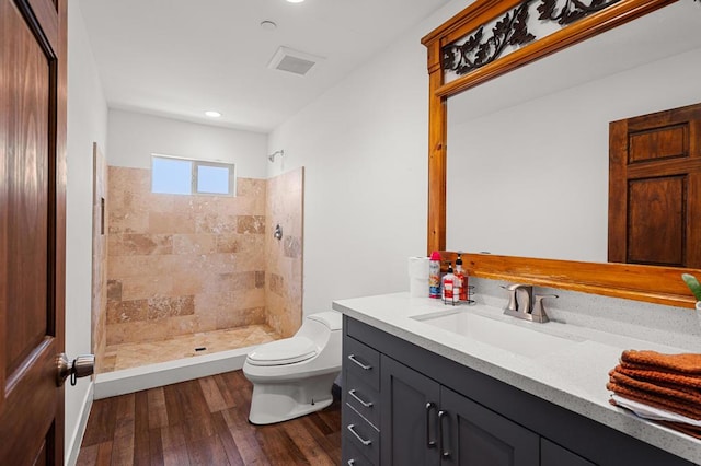 bathroom featuring vanity, toilet, wood-type flooring, and tiled shower