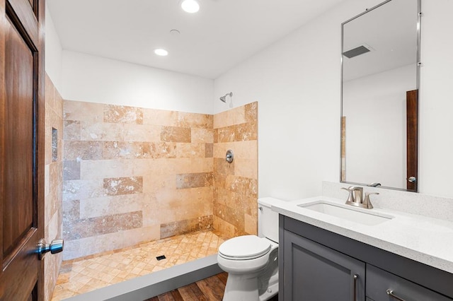 bathroom featuring vanity, toilet, wood-type flooring, and tiled shower