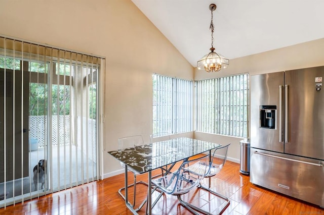 dining space with light hardwood / wood-style floors, high vaulted ceiling, and a chandelier