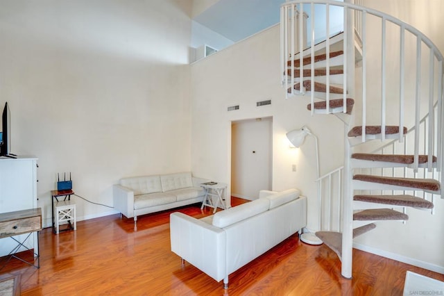 living room with hardwood / wood-style flooring and a towering ceiling