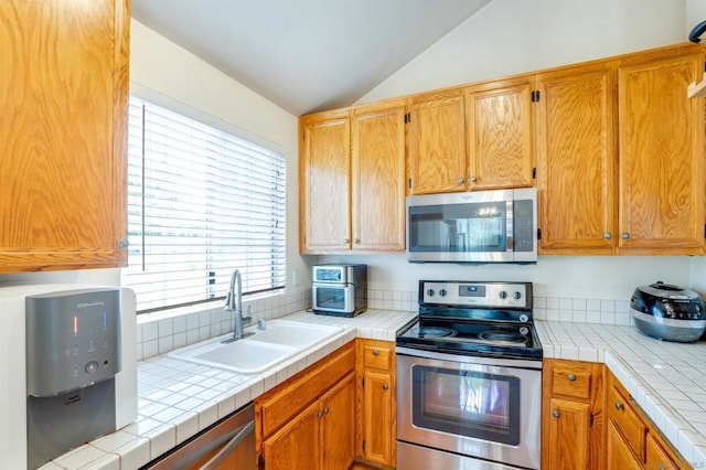 kitchen featuring tile counters, lofted ceiling, and appliances with stainless steel finishes