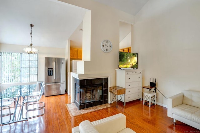 living room with a fireplace, light hardwood / wood-style floors, lofted ceiling, and a notable chandelier