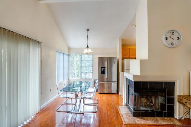 dining room featuring a chandelier, a fireplace, high vaulted ceiling, and light hardwood / wood-style flooring