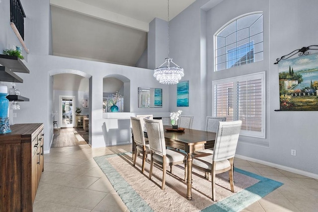 dining room featuring beamed ceiling, high vaulted ceiling, light tile patterned flooring, and an inviting chandelier