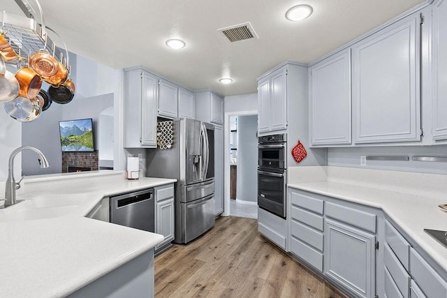 kitchen with kitchen peninsula, sink, light hardwood / wood-style flooring, and appliances with stainless steel finishes