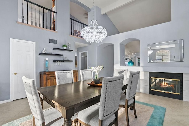 dining room with light tile patterned floors, beam ceiling, high vaulted ceiling, a fireplace, and a chandelier