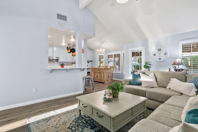 living room featuring beam ceiling, ceiling fan with notable chandelier, hardwood / wood-style flooring, and high vaulted ceiling