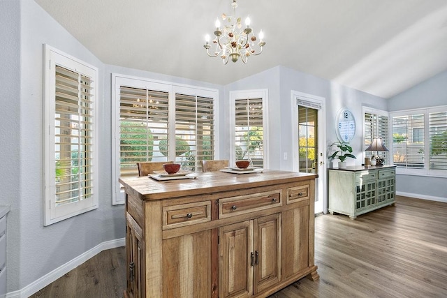 kitchen featuring hanging light fixtures, a healthy amount of sunlight, vaulted ceiling, and wood-type flooring