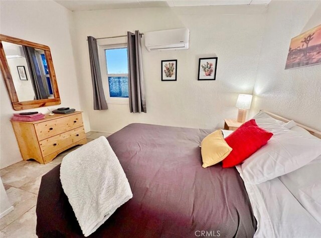 bedroom featuring light tile patterned floors and a wall mounted air conditioner