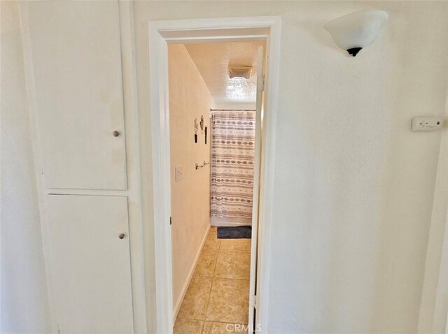 hall featuring light tile patterned flooring and a textured ceiling