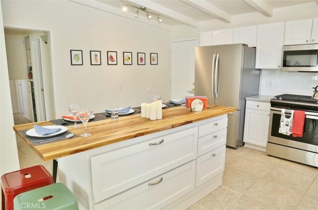 kitchen with beam ceiling, decorative backsplash, white cabinetry, appliances with stainless steel finishes, and wood counters