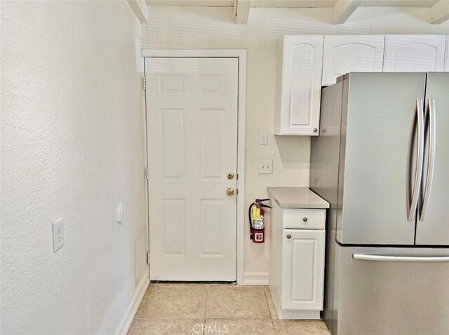 kitchen with light tile patterned floors, white cabinets, and stainless steel refrigerator