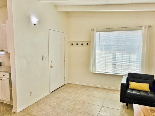 living area with light tile patterned floors, lofted ceiling with beams, and a wealth of natural light