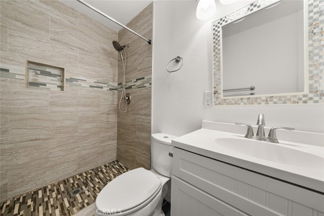 bathroom featuring a tile shower, vanity, and toilet